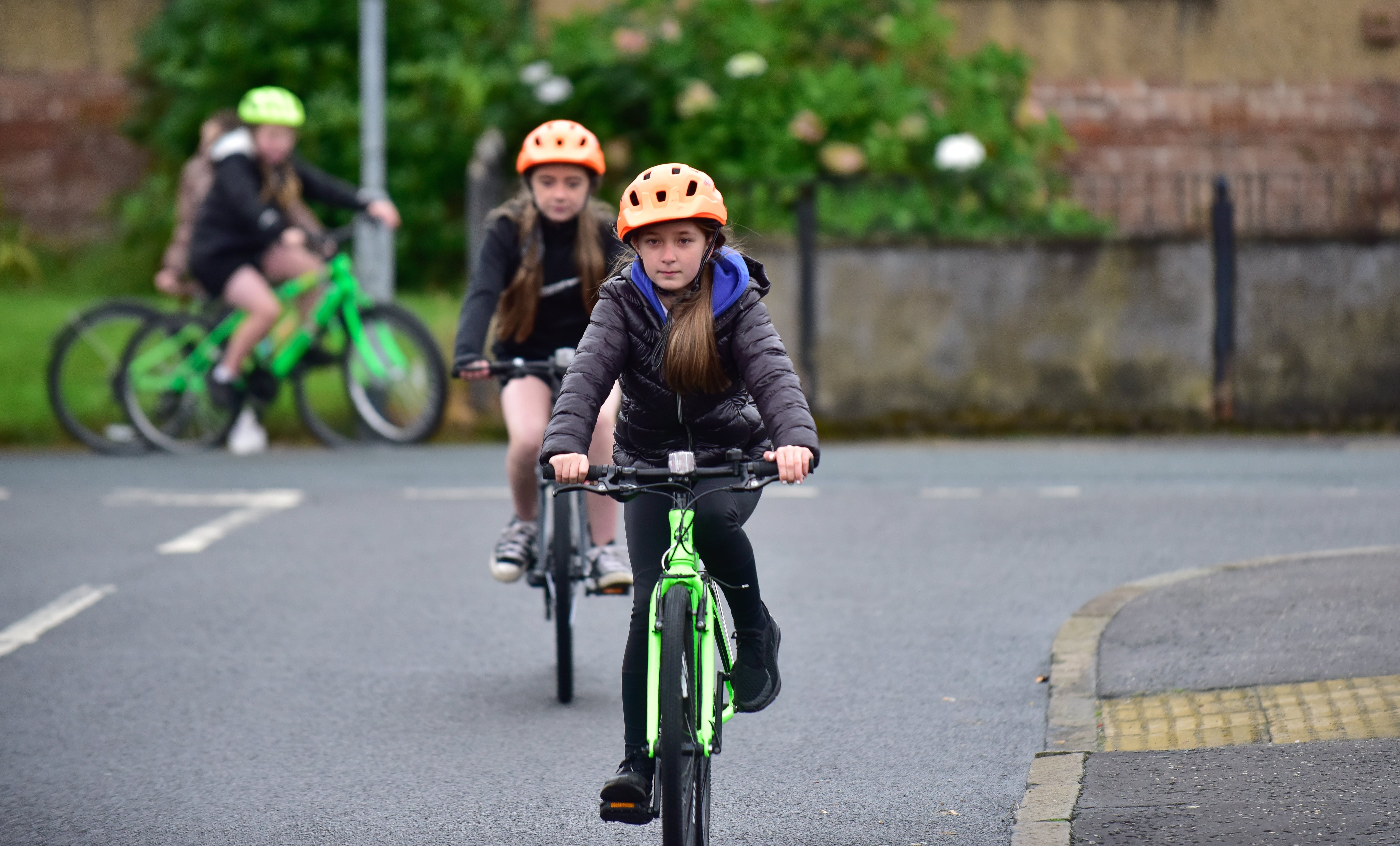 Two girls take part in Bikeability Scotland on-road cycle training on a residential street